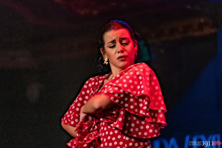 Bailaora de flamenco con vestido rojo de lunares en el Tablao Flamenco 1911 de Madrid, representando la estética de las sevillanas.