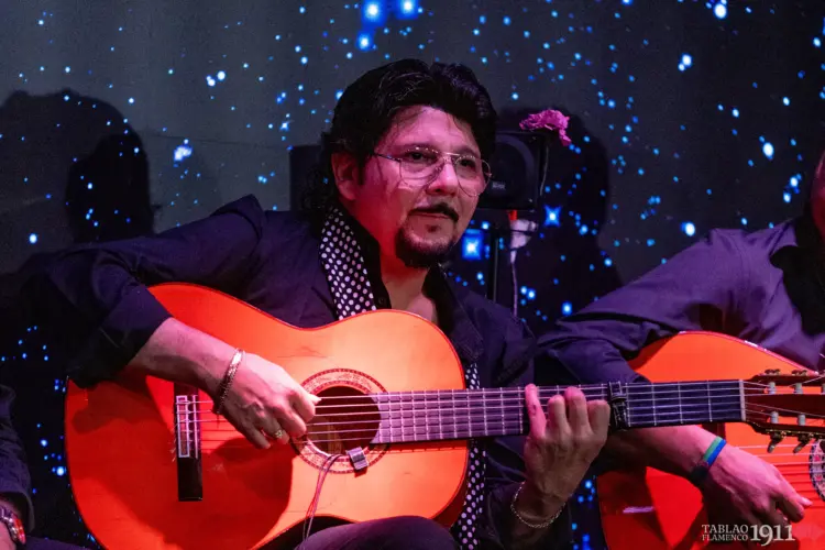 Fotografía del tocaor David Cerreduela tocando la guitarra flamenca en el escenario del Tablao Flamenco 1911. Viste camisa oscura y pañuelo de lunares al cuello, mostrando gran concentración durante el espectáculo en directo.