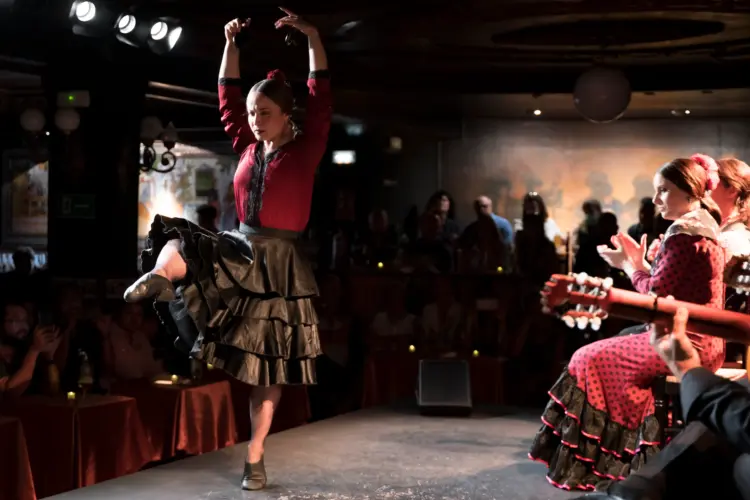 Female dancer performing with castanets on the stage of Tablao Flamenco 1911 in Madrid during the International Dance Day celebration, with live guitarist and singer