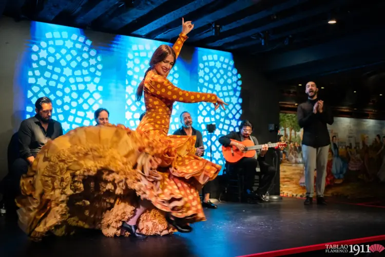 Bailaora Paula Rodríguez ejecutando un desplante con bata de cola roja en el escenario del Tablao Flamenco 1911 en Madrid.